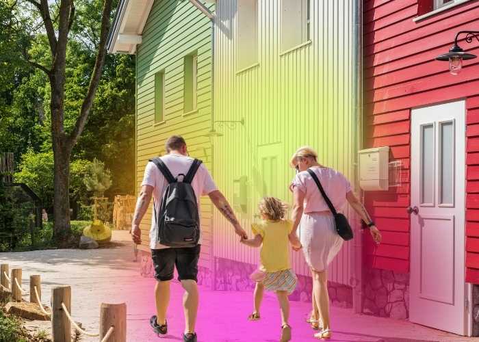 Familie von hinten zu sehen, die an bunten Häusern vorbeiläuft - mit einem farblichen Effekt hinterlegt