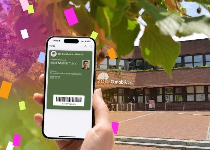 Jubiläumsrabatt auf Jahreskarten Mock-up einer Hand, die ein Handy mit einer digitalen Jahreskarte des Zoo Osnabrück hält vor einem Bild des Zooeingangs