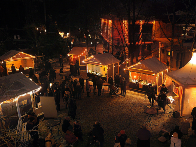 Blick von oben auf warm beleuchtete Weihnachtsmarktbuden im Zoo Osnabrück