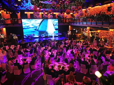 Eine Gala mit Tischen, Gästen und einer Bühne für Musiker.